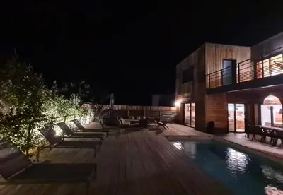 a pool with lounge chairs and a building at night at alcudina in Zonza