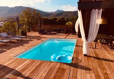 a swimming pool on a deck with a view of the mountains at alcudina in Zonza