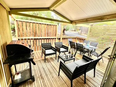 a screened in deck with a grill and tables and chairs at Chalet A tout confort à deux pas des plages in Pianottoli-Caldarello