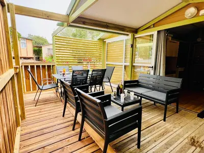 a patio with tables and chairs on a deck at Chalet A tout confort à deux pas des plages in Pianottoli-Caldarello