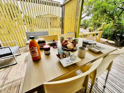 a table with food and a drink on a patio at Chalet N tout confort à deux pas des plages in Pianottoli-Caldarello
