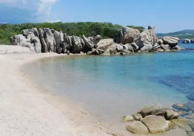 a beach with rocks in the water at Chalet N tout confort à deux pas des plages in Pianottoli-Caldarello