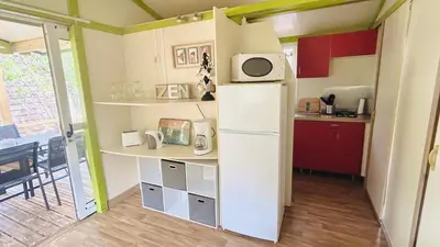 a small kitchen with a refrigerator and a table at Chalet M tout confort proche des plages in Pianottoli-Caldarello