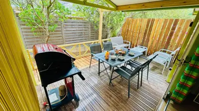 a patio with a table and a grill on a deck at Chalet M tout confort proche des plages in Pianottoli-Caldarello