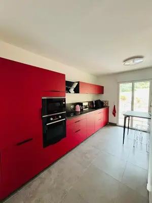 a kitchen with red cabinets and black counter tops at Acula Marina - Mer, Maquis Corse - T4 Lumineux in Ajaccio