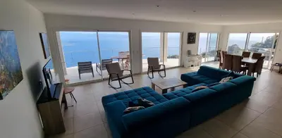 a living room with a blue couch and a dining room at Villa de standing piscine chauffée vue mer Corse du sud in Coti-Chiavari