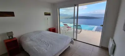a bedroom with a bed and a large window with a view at Villa de standing piscine chauffée vue mer Corse du sud in Coti-Chiavari