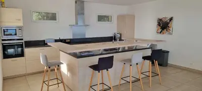 a kitchen with a counter with stools around it at Villa de standing piscine chauffée vue mer Corse du sud in Coti-Chiavari