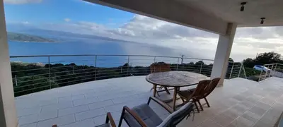 a table and chairs on a balcony with a view of the water at Villa de standing piscine chauffée vue mer Corse du sud in Coti-Chiavari