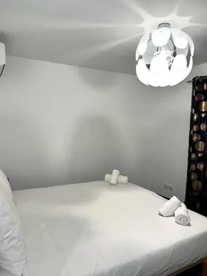a bedroom with a white bed and a chandelier at 9D - appartement Bonifacio Corse in Bonifacio