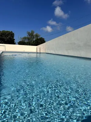 a swimming pool with blue water in front of a wall at 9D - appartement Bonifacio Corse in Bonifacio
