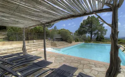 a swimming pool with chairs and an umbrella at A Machja 17 in Monacia-dʼAullène