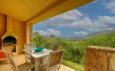 a patio with a table and chairs and a view of the mountains at A Machja 17 in Monacia-dʼAullène