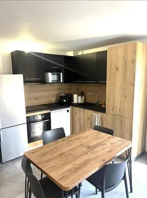 a kitchen with a wooden table and chairs at Les hameaux de Saint Cyprien - appartement avec jardin et piscine in Lecci