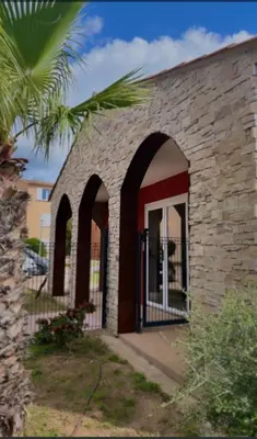 a brick building with arches and a palm tree at Les hameaux de Saint Cyprien - appartement avec jardin et piscine in Lecci