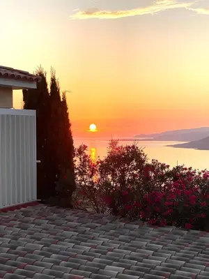 a sunset over the water with a house and flowers at Charmant appartement 3 étoiles entièrement rénové 