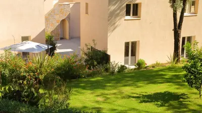 a garden in front of a building with an umbrella at Le 42e Parallèle in Valle-di-Mezzana