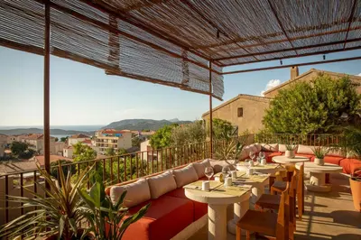 a restaurant with tables and chairs on a balcony at Hôtel Mylos - Cargèse, Piscine Intérieure et Extérieure in Cargèse