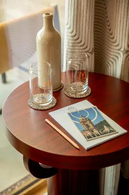a table with two glasses and a book and a vase at Hôtel Mylos - Cargèse, Piscine Intérieure et Extérieure in Cargèse