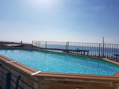 a large swimming pool with the ocean in the background at Appartement VOILES BLANCHES-Clim-Wifi-Plage a pieds in Sari Solenzara