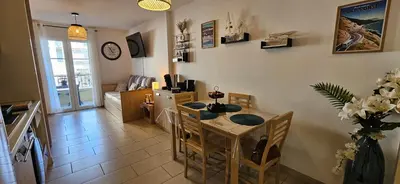 a living room with a table and a dining room at Appartement VOILES BLANCHES-Clim-Wifi-Plage a pieds in Sari Solenzara