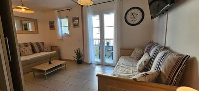 a living room with a couch and a clock on the wall at Appartement VOILES BLANCHES-Clim-Wifi-Plage a pieds in Sari Solenzara