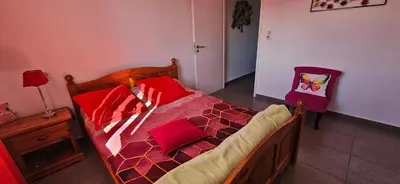 a bedroom with a bed with red pillows and a chair at VERANU - Vue campagne- 5 mn de la plage de sable in Prunelli-di-Fiumorbo