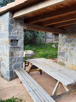 a wooden picnic table under a stone building at Authentique Casellu en pierre à Porticcio avec vue sur la mer in Porticcio