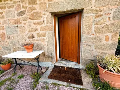 a door and a table in front of a stone building at Authentique Casellu en pierre à Porticcio avec vue sur la mer in Porticcio