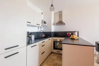 a kitchen with white cabinets and black counter tops at Cosy T2 vue mer climatisé wifi et tout équipé refait à neuf in Ajaccio