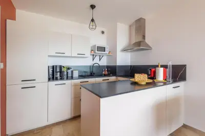 a kitchen with white cabinets and a black counter top at Cosy T2 vue mer climatisé wifi et tout équipé refait à neuf in Ajaccio