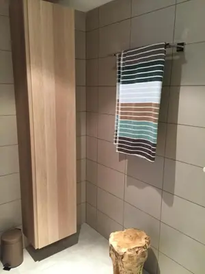 a bathroom with a shower with a towel and a stool at Neues, modernes Steinchalet mit grosser Terrasse und Pool bei Rondinara in Bonifacio