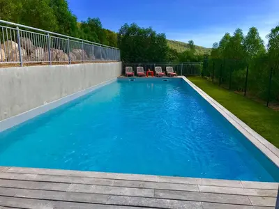 a swimming pool with two chairs and a fence at Neues, modernes Steinchalet mit grosser Terrasse und Pool bei Rondinara in Bonifacio