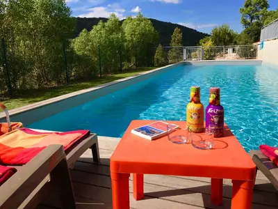 a table with two bottles on it next to a swimming pool at Neues, modernes Steinchalet mit grosser Terrasse und Pool bei Rondinara in Bonifacio