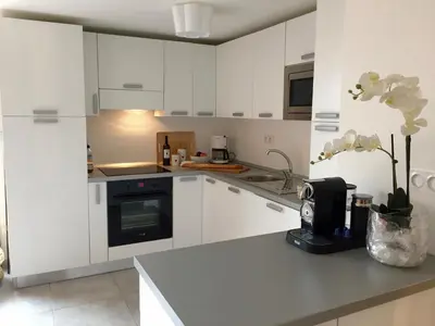 a kitchen with white cabinets and a counter with flowers at Neues, modernes Steinchalet mit grosser Terrasse und Pool bei Rondinara in Bonifacio