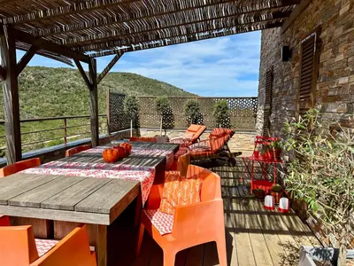 a patio with a wooden table and chairs on a deck at Neues, modernes Steinchalet mit grosser Terrasse und Pool bei Rondinara in Bonifacio