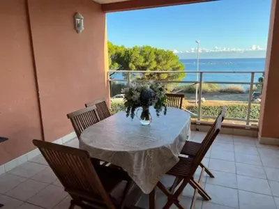 a table with chairs and a vase of flowers on a balcony at Ajaccio appartement vue mer in Ajaccio