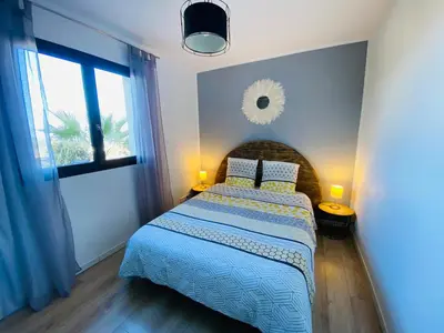 a bedroom with a bed with a blue comforter and a window at Magnifique appartement vue mer et montagne à Solenzara Corse in Sari Solenzara