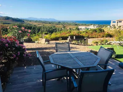 a table and chairs on a patio with a view of the ocean at Beautiful apartment U Mare sea and mountain view in Sari Solenzara