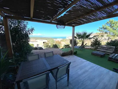 a patio with a table and chairs on a deck at Beautiful apartment U Mare sea and mountain view in Sari Solenzara