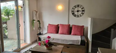 a bedroom with a bed with red pillows and a clock at Mini villa Vue Mer Santa Giulia - Accès plage à pied - 2 à 4 pers - 1 chambre in Porto-Vecchio
