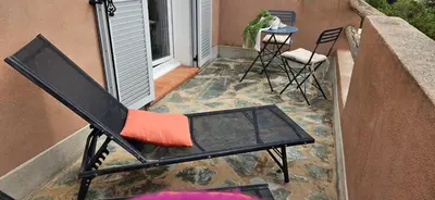 a black chair sitting on a balcony with a table at Mini villa Vue Mer Santa Giulia - Accès plage à pied - 2 à 4 pers - 1 chambre in Porto-Vecchio