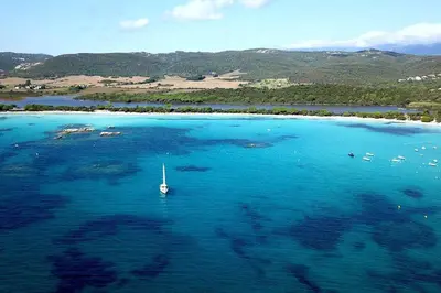 an island with a sail boat in the water at Mini villa Vue Mer Santa Giulia - Accès plage à pied - 2 à 4 pers - 1 chambre in Porto-Vecchio