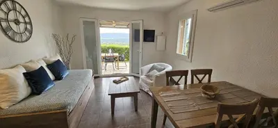 a living room with a couch and a table at Mini villa Vue Mer Santa Giulia - Accès plage à pied - 2 à 4 pers - 1 chambre in Porto-Vecchio