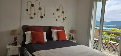 a bedroom with a bed with colorful pillows and a balcony at Mini villa Vue Mer Santa Giulia - Accès plage à pied - 2 à 4 pers - 1 chambre in Porto-Vecchio