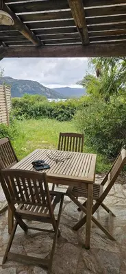 a wooden table and two chairs on a patio at Mini villa Vue Mer Santa Giulia - Accès plage à pied - 2 à 4 pers - 1 chambre in Porto-Vecchio