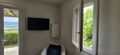a room with a window and a television on the wall at Mini villa Vue Mer Santa Giulia - Accès plage à pied - 2 à 4 pers - 1 chambre in Porto-Vecchio