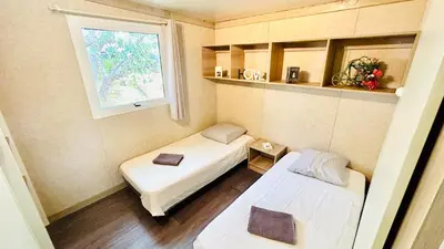 a small room with two beds and a window at Chalet V tout confort proche des plages in Pianottoli-Caldarello