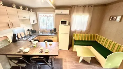 a small kitchen with a table and a refrigerator at Chalet V tout confort proche des plages in Pianottoli-Caldarello