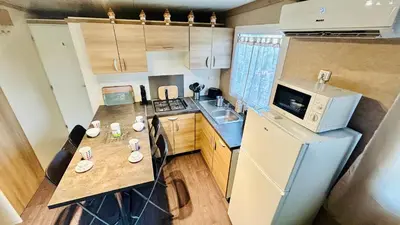 a small kitchen with a table and a refrigerator at Chalet V tout confort proche des plages in Pianottoli-Caldarello